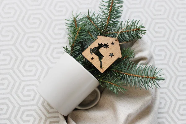 Hafif bir kumaş üzerinde bir fincan ve köknar dallarıyla şık bir arka plan. Noel arkaplanı.