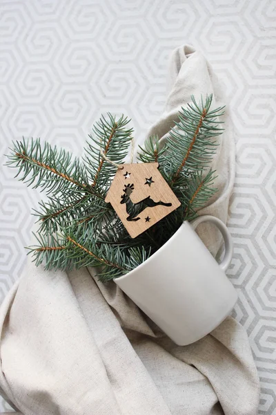Hafif bir kumaş üzerinde bir fincan ve köknar dallarıyla şık bir arka plan. Noel arkaplanı.