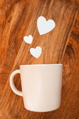 Beyaz kalp, ahşap bir arka planda, bir kupadan dışarı uçar. 14 Şubat 'ta, kayıt için yer alan yaratıcı bir altyapıya sahip beyaz kalp, ahşap bir arka planda kupadan uçup gidiyor. Kayıt için yer alan 14 Şubat yaratıcı arka plan.