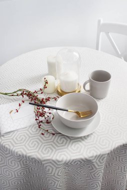 Masada beyaz bir masa örtüsü ve kırmızı böğürtlen dalı olan tabaklar yuvarlak masa, daire içi parlak renklerde servis ediliyor.