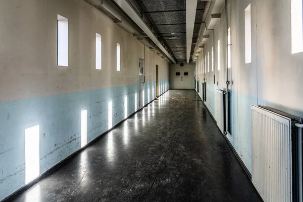 A long bare corridor with light and dark shadow spots. The corridor evokes an unpleasant and anxious feeling — Stock Photo, Image