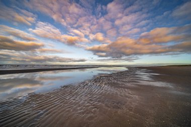 Kumsal, bulutlu gökyüzü ve sahil.