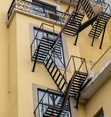 Bir apartmanın ön cephesinde yangın merdivenleri var.