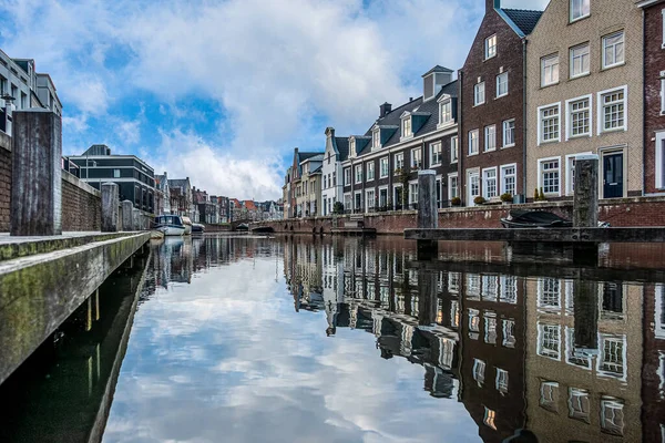 Typical dutch houses along side a canal in a dutch city under a blue and cloudy sky