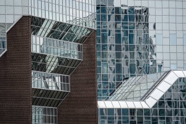 Modern bir ofis binasının ön cephesinin bir parçası, dış görünüşü yansıtıyor.
