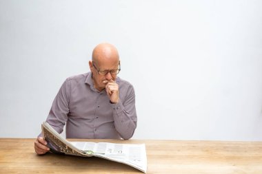 Beyaz erkek, masa başında oturmuş bir fincan kahve içerken gazete okuyor..