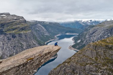 Trolltunga kaya (Troll dil rock) üzerinde oturan ve Norveç dağ manzarası arayan adam