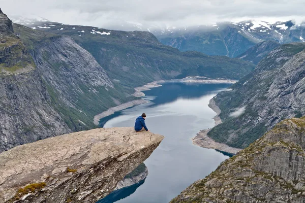 Ο άνθρωπος κάθεται σε βράχο χώρου (Trolltunga) (Troll του γλώσσα ροκ) και κοιτάζοντας Νορβηγικά ορεινό τοπίο — Φωτογραφία Αρχείου