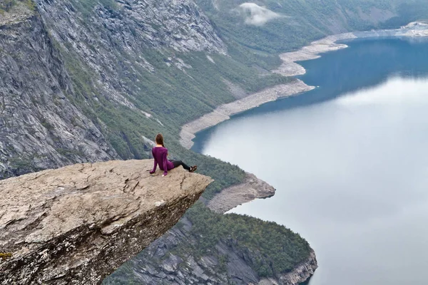 Κορίτσι που κάθεται σε βράχο χώρου (Trolltunga) (Troll του γλώσσα ροκ) και κοιτάζοντας Νορβηγικά ορεινό τοπίο — Φωτογραφία Αρχείου