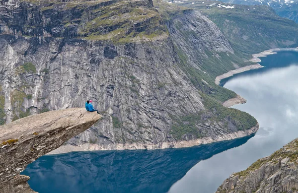 Άνθρωποι που κάθεται σε βράχο χώρου (Trolltunga) (Troll του γλώσσα ροκ) και κοιτάζοντας Νορβηγικά ορεινό τοπίο — Φωτογραφία Αρχείου