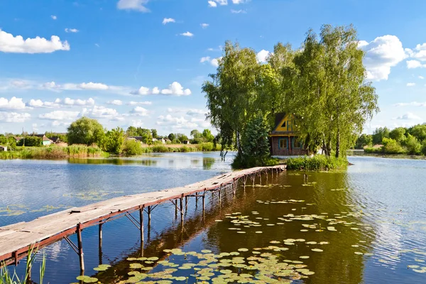 Adadaki küçük ev. Göl kenarındaki eve giden köprü manzarası. Adadaki eski ahşap balıkçı ve avcı evi. Eski Solotvyn Köyü, Ukrayna