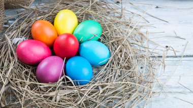 Saman ahşap arka plan üzerinde renkli Paskalya yumurtaları