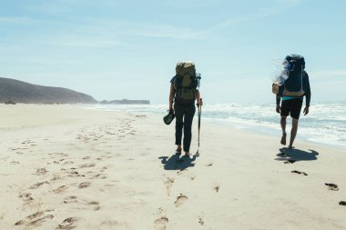 Kumsalda yürüyen iki turist.