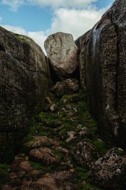 Norveç 'te mavi gökyüzüne karşı dağların arasına sıkışmış büyük bir kaya yığını.