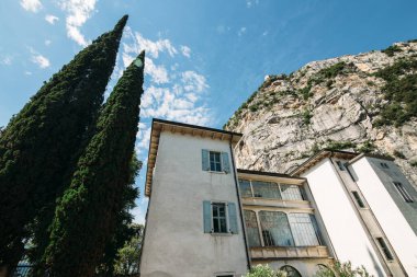 İtalya 'da mavi gökyüzünün arka planında, dağın altındaki selvi ağacının yanındaki eski ev.