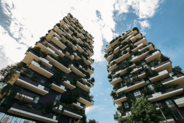 Şehrin balkonlarında mavi gökyüzüne karşı bitkilerle dolu iki ev.