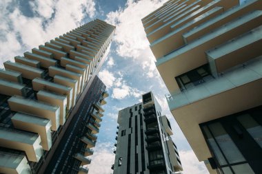 Üç gökdelen, aşağıdan güneşe karşı mavi bir gökyüzü.