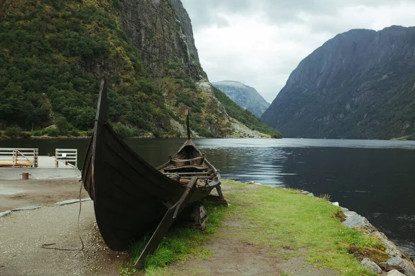 Nehrin arka planında eski Norveç Viking teknesi, dağlar ve mavi gökyüzü