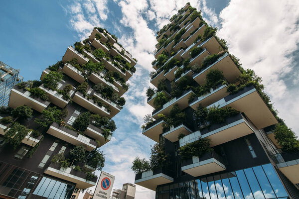 два дома с растениями на балконах в городе против голубого неба
