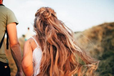 Beyaz elbiseli kız, saçları dağdan gökyüzüne doğru koşuyor.