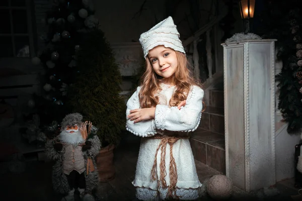 Noel Baba ve Noel ağacının arka planında merdivenlerin yanında duran Noel kostümlü küçük kız.