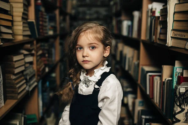 Dziewczyna Szkolnym Mundurze Siedzi Stołku Między Półkami Książkami Szkołą Biblioteką — Zdjęcie stockowe