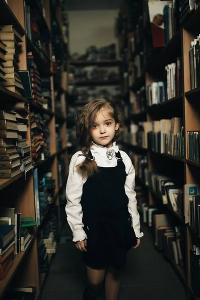 Dziewczyna Mundurze Szkolnym Stoi Między Półkami Książkami Szkołą Biblioteką — Zdjęcie stockowe