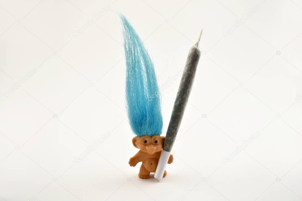 Troll with marijuana stock images. Elf on a white background. Troll with blue hair. Marijuana isolated on a white background. Funny troll with a joint