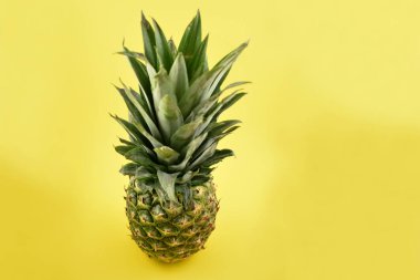 Sarı arkaplandaki fotoğraf resimlerinde taze ananas var. Metin için kopyalama alanı olan sarı arkaplan üzerindeki ananas