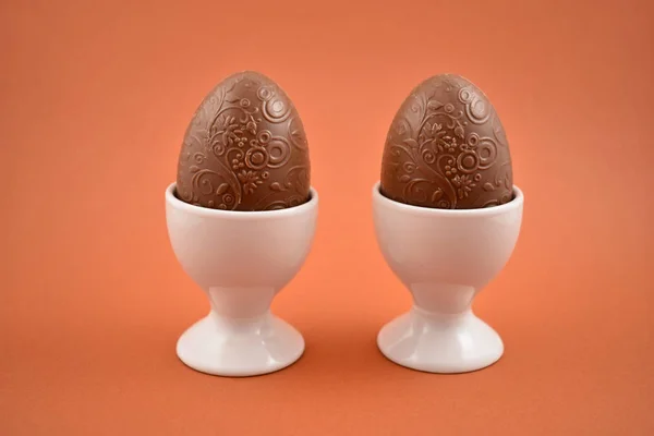 Chocolate egg in an egg holder stock images. Easter egg on a brown background. Breakfast still life. Easter concept. Two chocolate eggs