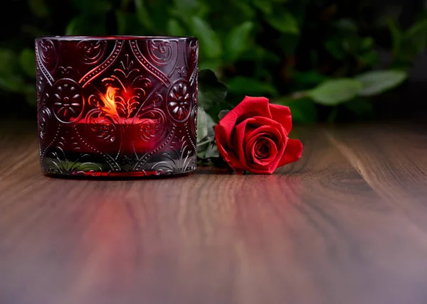 Red rose with candle on a wooden background stock images. Romantic still life with red rose and candle cup holder. Valentine\'s Day concept. Valentines Day backgound with copy space for text