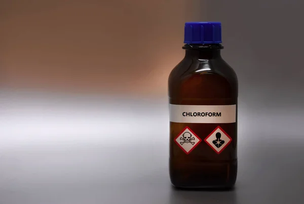 Chloroform in brown laboratory bottle stock images. A bottle of chloroform with inscription. Brown lab bottle. Brown glass container. Phial with warning pictograms on a silver background