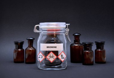 Bromine bottle stock images. Toxic liquid stock images. Brown lab bottle. Brown glass container. Phial with warning pictograms on a black background. Laboratory accessories