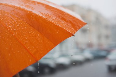 Parlak turuncu bir şemsiyeden düşen yağmur damlaları