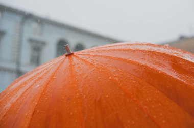 turuncu bir şemsiye düşen yağmur damlaları
