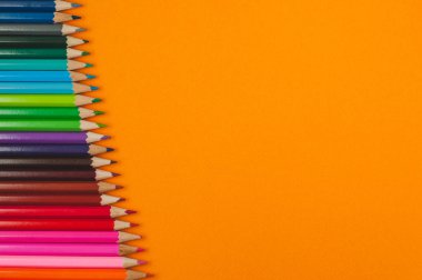 Turuncu doku arka plan üzerinde renkli kalemler