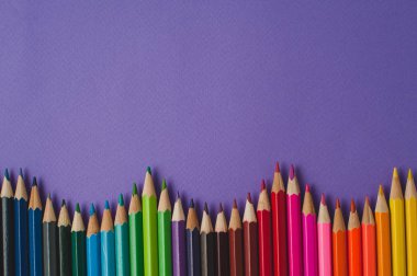 Mor doku arka plan üzerinde renkli kalemler