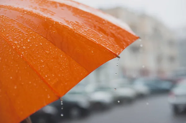 Parlak turuncu bir şemsiyeden düşen yağmur damlaları