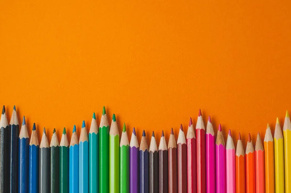 Lápis coloridos sobre um fundo de mostarda . — Fotografia de Stock