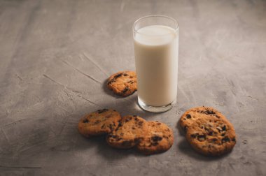Gri çimento arka planda çikolatalı bir bardak süt ve kurabiye