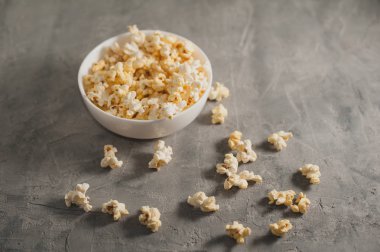 Beton arkaplanda beyaz bir tabakta patlamış mısır.