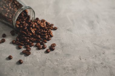 Kahve çekirdekleri gri bir zemine saçılmış.