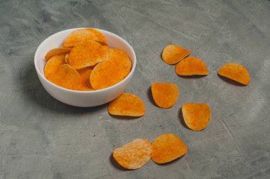 Gri beton bir masada patates cipsi.