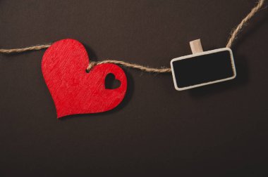 bir ip ve küçük yazı tahtası siyah bir arka plan üzerinde kırmızı kalp