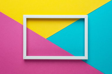 Parlak sarı, pembe, mavi arkaplan üzerine boş beyaz çerçeve. Düz yatıyordu. Moda minimumu konsept. Metin veya tasarım için boşluk kopyala.