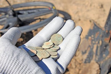 Metal dedektörü kullanırken paraları tutan adamın yakın çekim