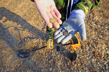 Metal dedektörü kullanırken paraları tutan adamın yakın çekim