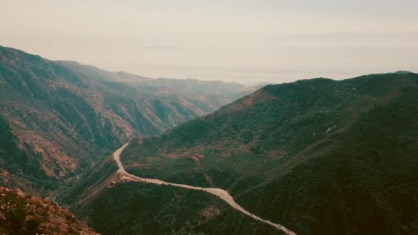 Kino lotnicze panoramiczne wideo widok na górskie formacje w Malibu z helikoptera. Górska droga biegnie wzdłuż górnej części wzgórza. Los Angeles, California, Stany Zjednoczone Ameryki — Wideo stockowe