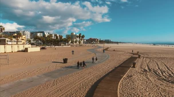 Toeristen lopen langs het pad op het strand in de buurt van Santa Monica pier. — Stockvideo