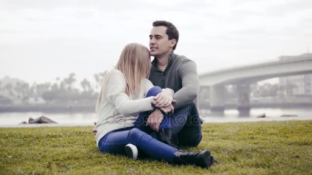 Két szerelmes ül a fűben, és átölelte a parkban — Stock videók